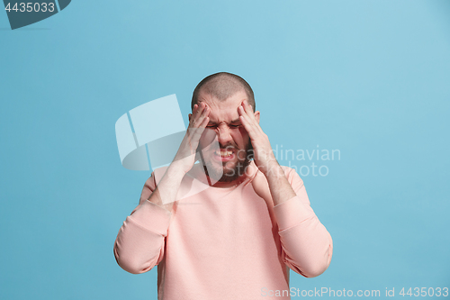 Image of Man having headache. Isolated over blue background.