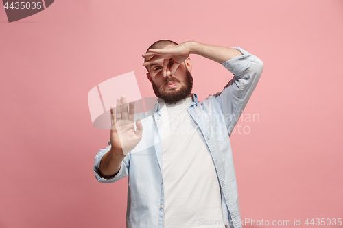 Image of Young man with disgusted expression repulsing something, isolated on the pink