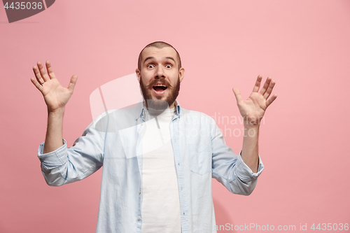 Image of The young attractive man looking suprised isolated on pink