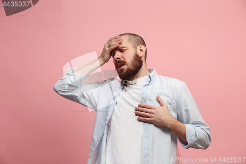 Image of Man having headache. Isolated over pink background.