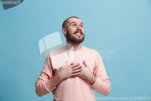 Image of The happy business man standing and smiling against blue background.