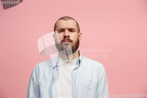 Image of The serious businessman standing and looking at camera against pink background.