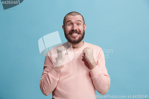 Image of The happy business man standing and smiling against blue background.