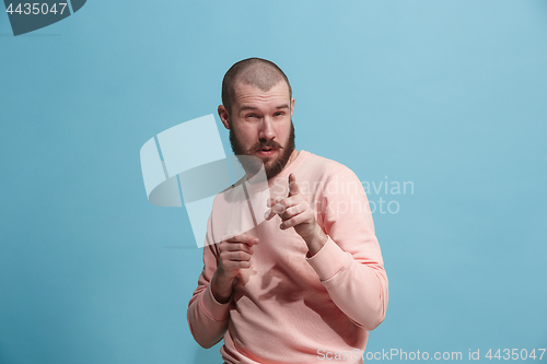 Image of Suspiciont. Doubtful pensive man with thoughtful expression making choice against blue background