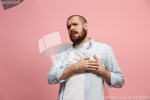 Image of Man having heart pain. Isolated over pink background.