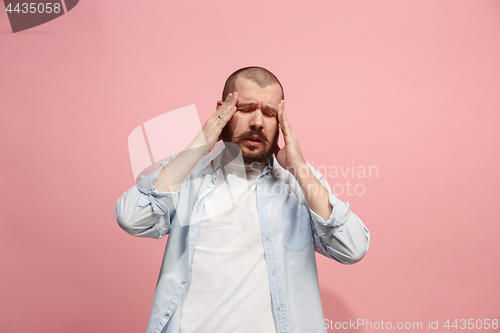 Image of Man having headache. Isolated over pink background.