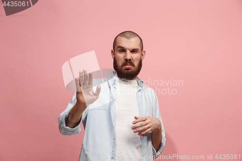 Image of Young man with disgusted expression repulsing something, isolated on the pink