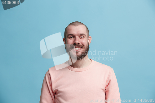 Image of The happy business man standing and smiling against blue background.