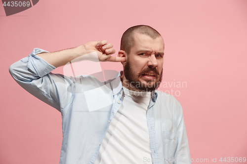 Image of The Ear ache. The sad man with headache or pain on a pink studio background.