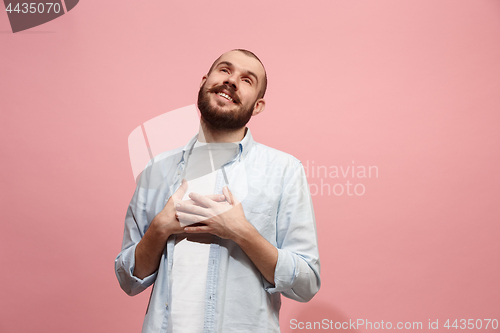 Image of The happy businessman standing and smiling against pink background.