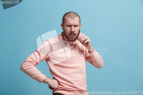 Image of Suspiciont. Doubtful pensive man with thoughtful expression making choice against blue background