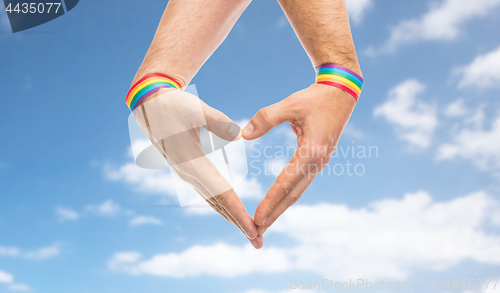 Image of male hands with gay pride wristbands showing heart