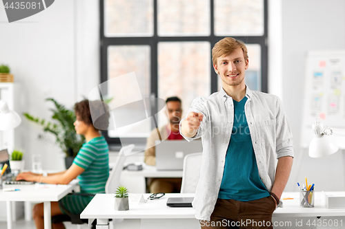 Image of happy smiling man pointing finger at you at office