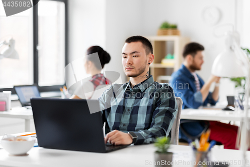 Image of creative man with laptop working at office