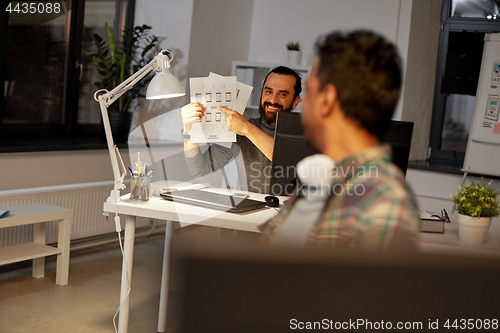 Image of creative man showing papers to colleague at office