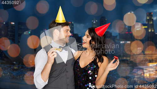 Image of happy couple with party blowers having fun