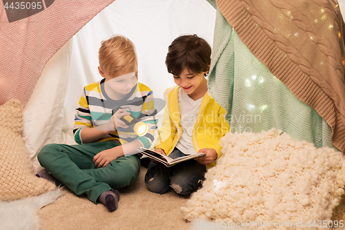 Image of happy boys reading book in kids tent at home