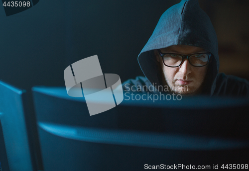 Image of close up of hacker in hood at computer monitor