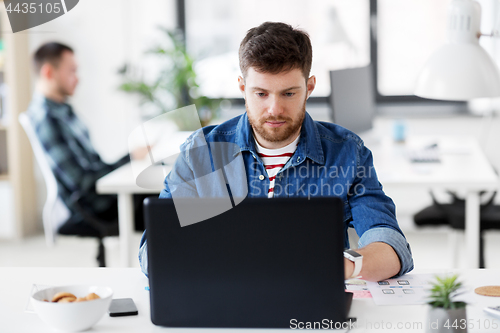 Image of creative man with laptop working at office