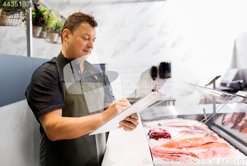 Image of seller with clipboard selling seafood at fish shop