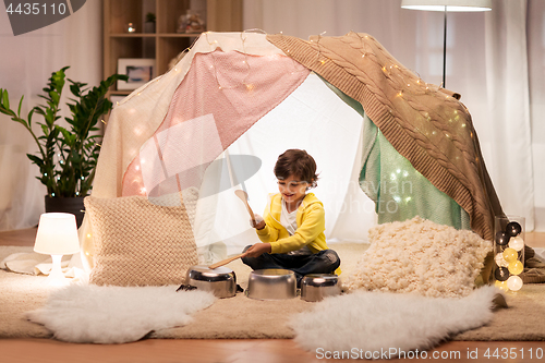Image of boy with pots playing music in kids tent at home