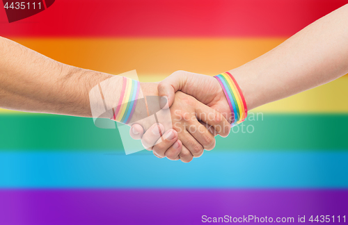 Image of hands with gay pride wristbands make handshake