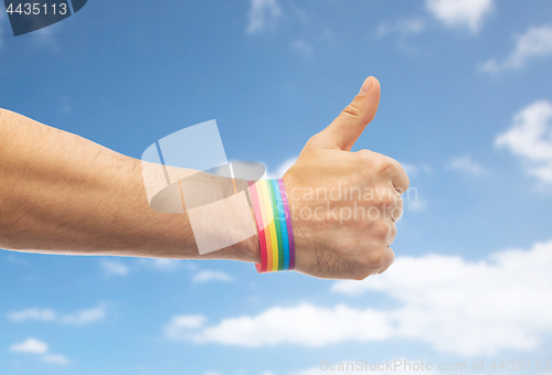 Image of hand with gay pride rainbow wristband shows thumb