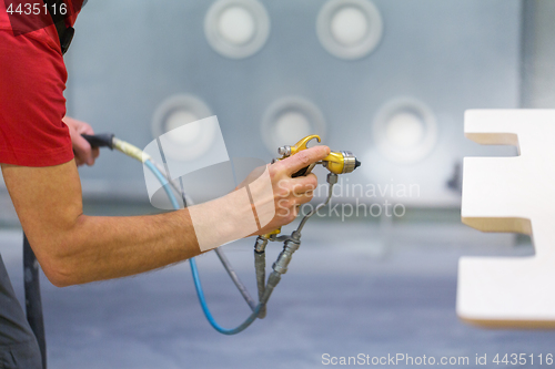 Image of worker hand sprays urethane finish to board