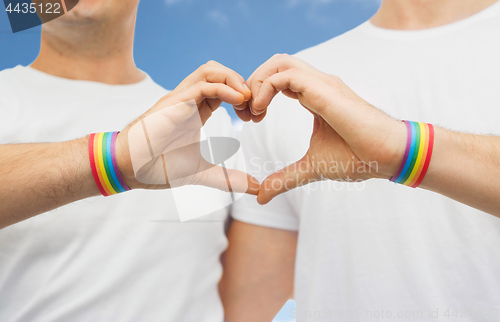 Image of gay couple with rainbow wristbands and hand heart