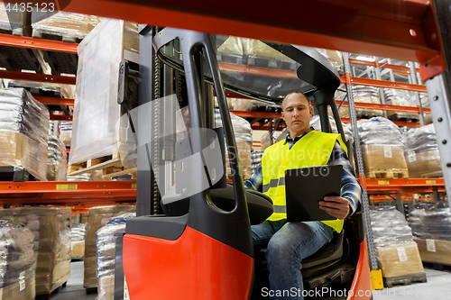 Image of loader with clipboard in forklift at warehouse