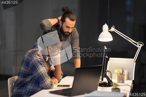 Image of creative team with computer working late at office