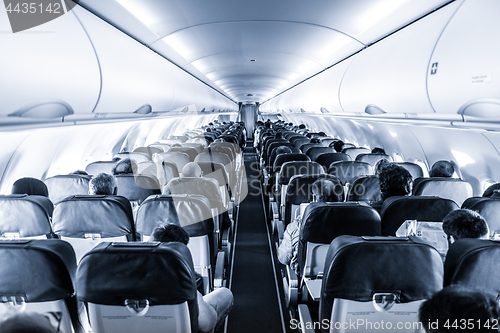 Image of Interior of commercial airplane with passengers on their seats during flight.