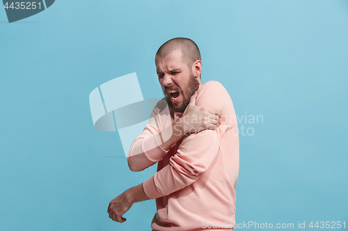 Image of Young man overwhelmed with a pain in the shoulder .