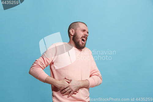 Image of Young man overwhelmed with a pain in the stomach .