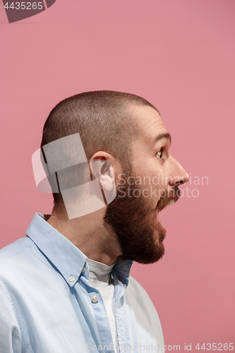 Image of The young emotional surprising man screaming on pink studio background