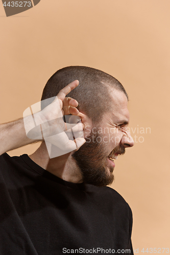 Image of The Ear ache. The sad man with headache or pain on a pastel studio background.
