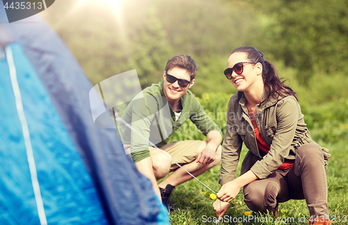 Image of happy couple setting up tent outdoors