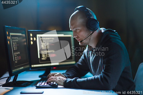 Image of hacker with computer and headset in dark room