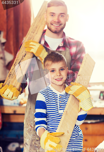 Image of happy father and son with wood plank at workshop