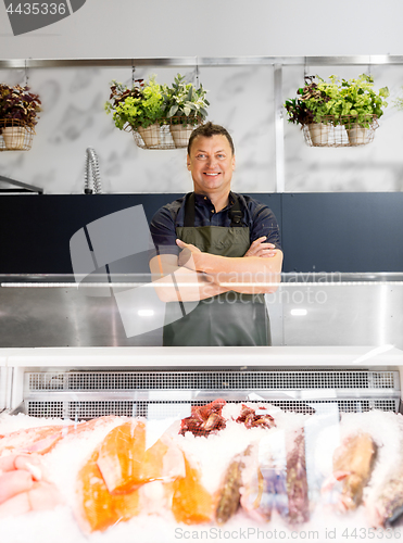 Image of male seller with seafood at fish shop fridge