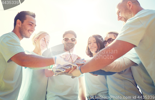 Image of group of volunteers putting hands on top outdoors