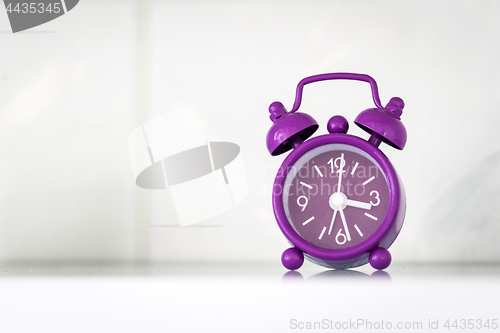 Image of Purple alarm clock in a bright room