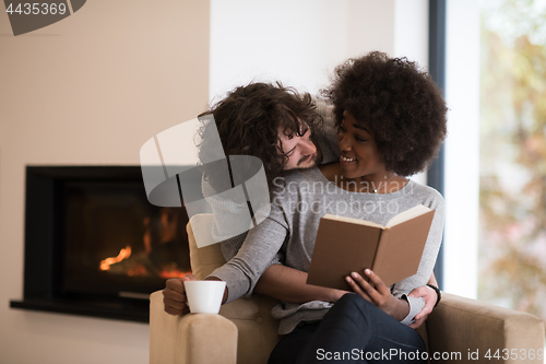 Image of multiethnic couple hugging in front of fireplace