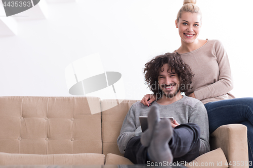 Image of couple relaxing at  home with tablet computers