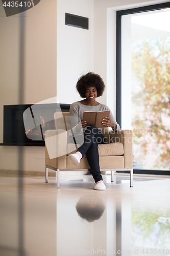 Image of black woman at home reading book