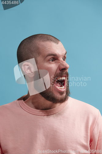 Image of The young emotional angry man screaming on blue studio background