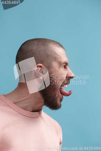 Image of The young emotional angry man screaming on blue studio background