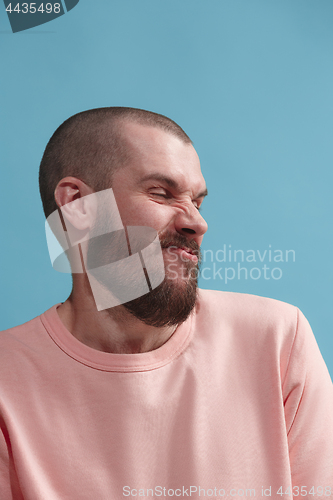 Image of Young man with disgusted expression repulsing something, isolated on the blue