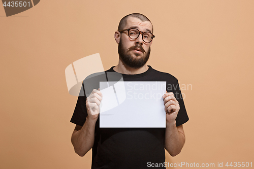 Image of A young man holds an empty plate in his hands to fill your text. Emotional, courageous face.