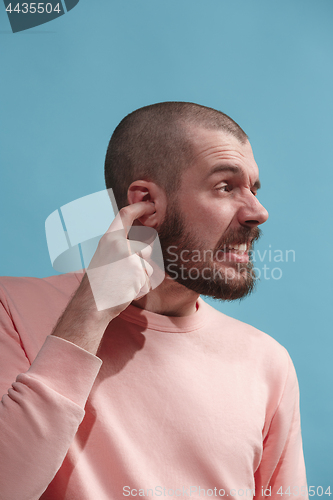 Image of The Ear ache. The sad man with headache or pain on a blue studio background.